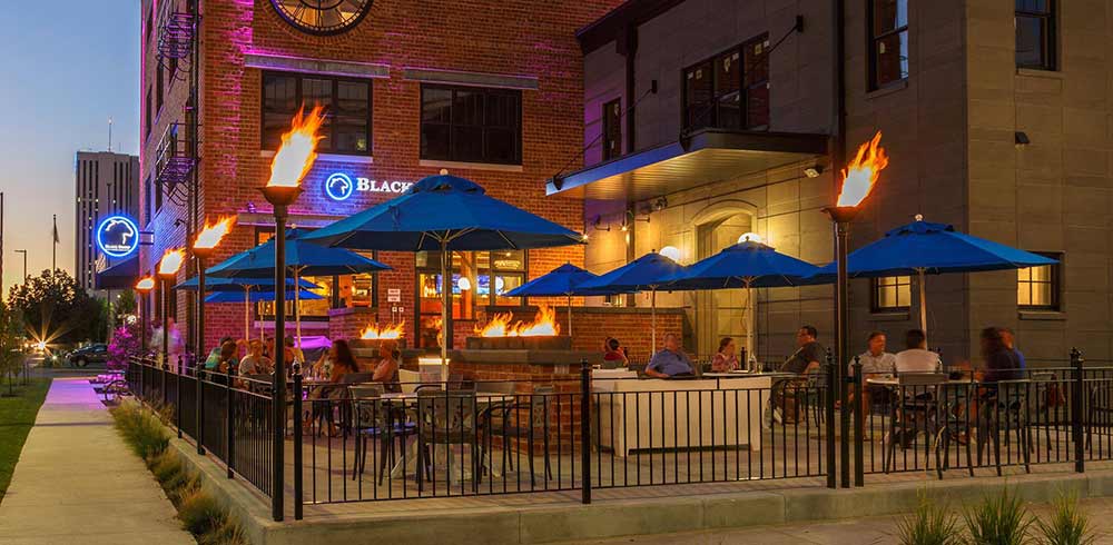 black sheep social club cedar rapids iowa outdoor patio with fire pits and torches at night